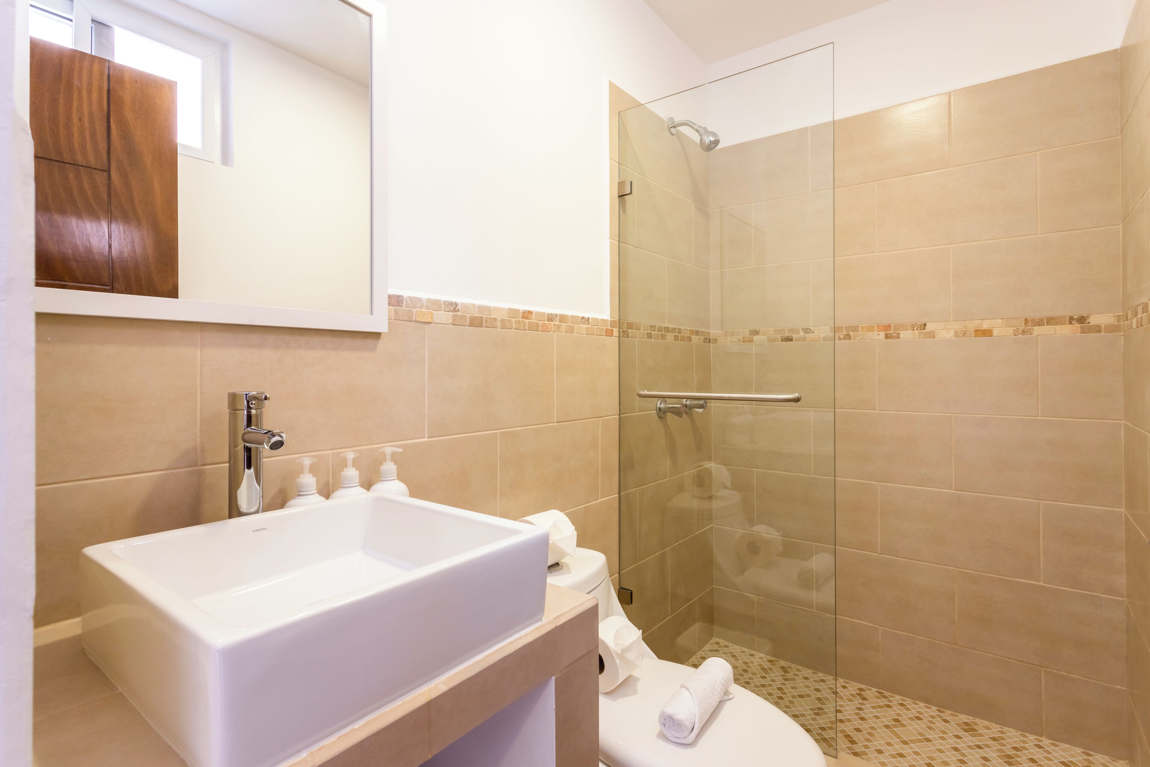 A bathroom with a large white sink, a glass shower enclosure, and a toilet.