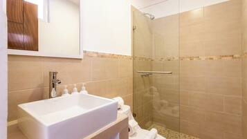 A bathroom with a large white sink, a glass shower enclosure, and a toilet.