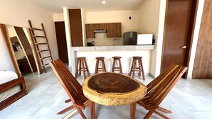 Une cuisine moderne dotée d’un îlot central, de tabourets de bar et d’une table à manger avec des chaises en bois.