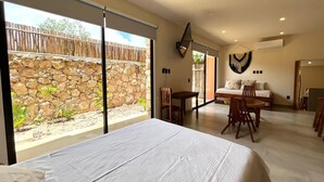 Une pièce spacieuse avec un grand lit, un coin repas et une vue sur un mur de pierre et un jardin.