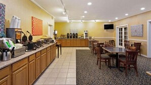 A hotel room with a kitchenette, a dining area with chairs, and a TV mounted on the wall. - University Inn & Suites Berkeley (Berkeley)