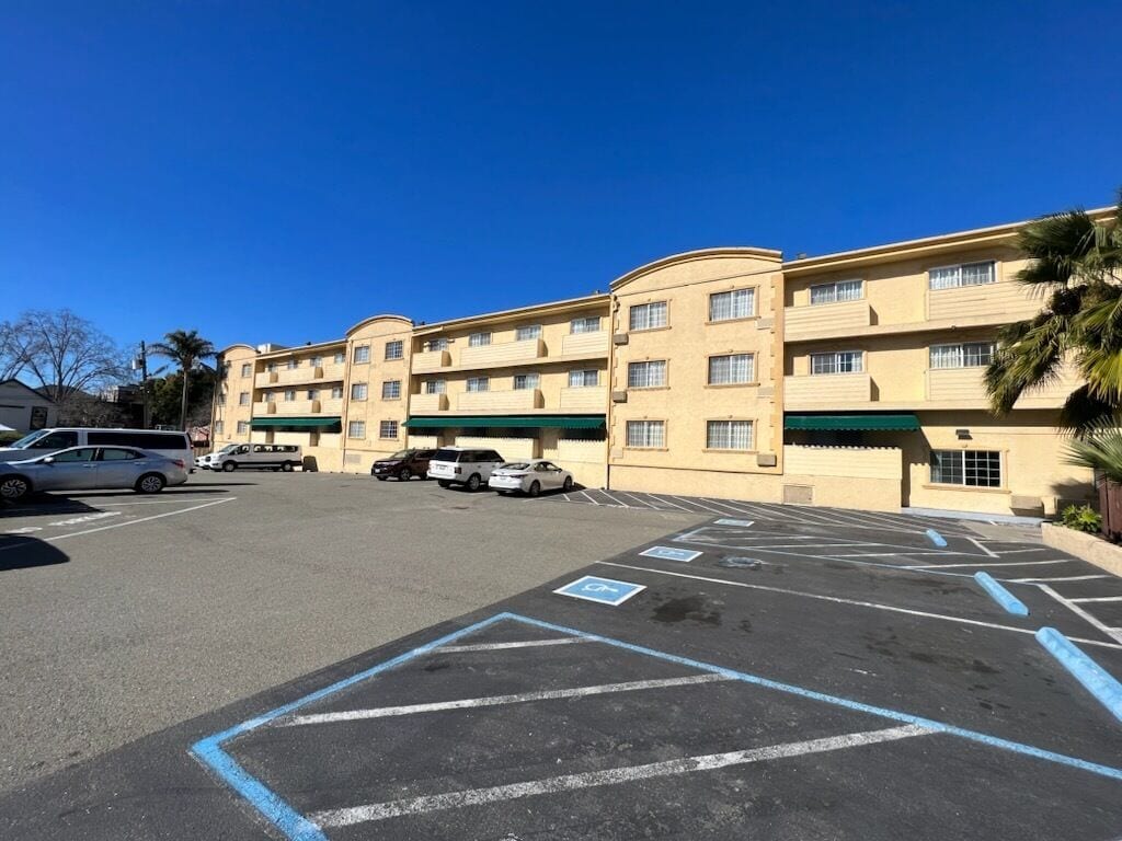 A multi-story hotel with a parking lot in front.