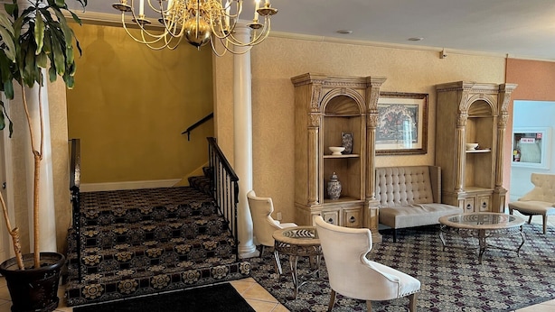 A grand foyer with a chandelier, a staircase, and a seating area with a round table. - University Inn & Suites Berkeley (Berkeley)