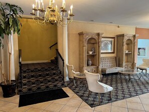 Un vaste hall d’entrée agrémenté d’un lustre, d’un escalier et d’un espace salon avec une table ronde.