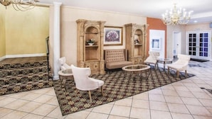 A spacious lobby with a patterned carpet, a seating area with a sofa and chairs, and a chandelier. - University Inn & Suites Berkeley (Berkeley)