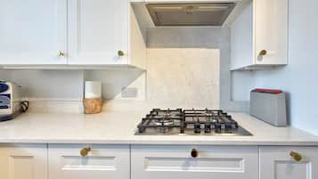 A kitchen with white cabinets, a gas stove, and a toaster.