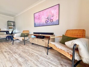 Ein Wohnzimmer mit einer Couch, einem Couchtisch und einem an der Wand befestigten Fernseher.