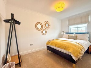A bedroom with a bed, a standing lamp, and wall decor.