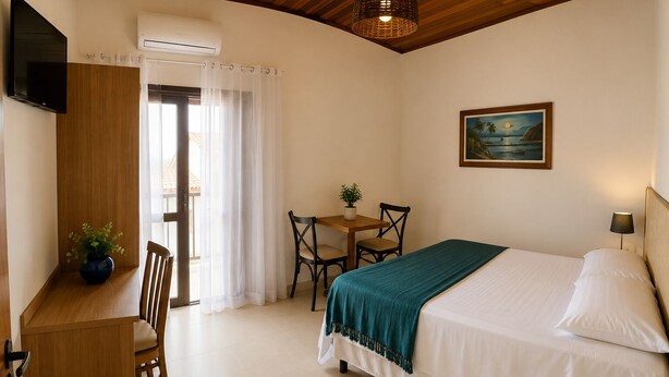 A bedroom with a bed, a desk, a chair, a table, a potted plant, and a painting on the wall.