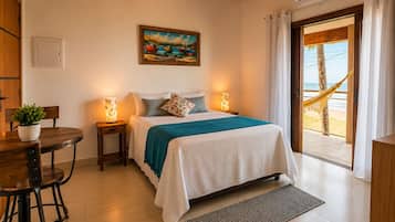 Une chambre avec un lit, des lampes de chevet, un tableau, une vue sur la plage et un coin repas avec une table et des chaises.