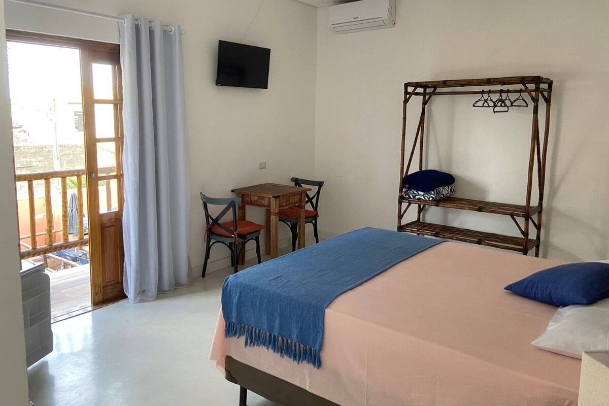 Une chambre à coucher avec un lit, une télévision, une table avec des chaises et une chaise en bois.