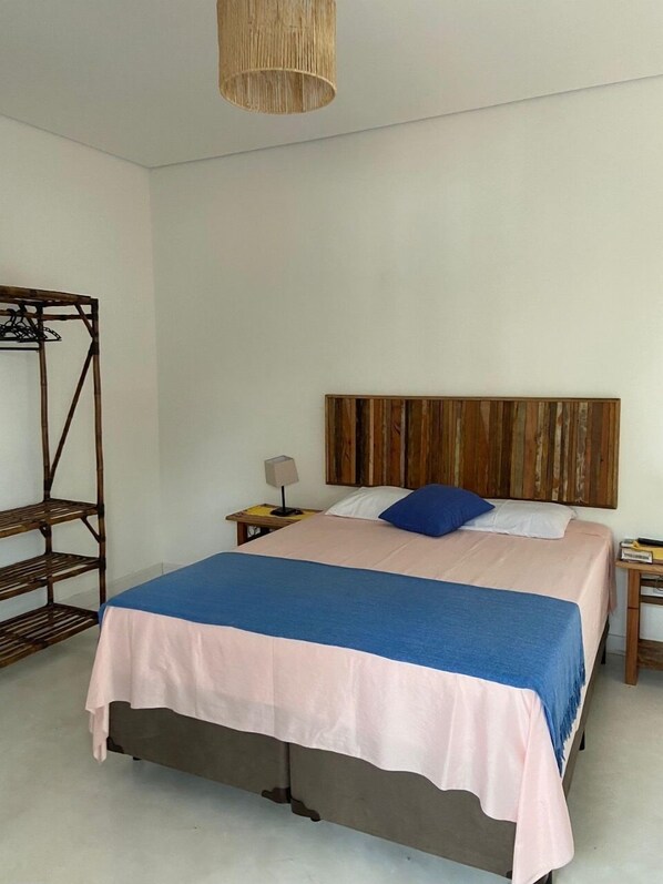 Une chambre à coucher comprenant un lit, une tête de lit en bois, une table de chevet avec une lampe et une étagère en bois.