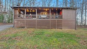 A wooden cabin with a balcony, a covered porch, and a small deck area.