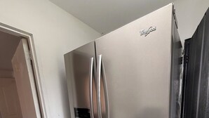 A stainless steel Whirlpool refrigerator in a kitchen with white walls and tiled flooring. - Beautiful countryside stay at La Milonga Finca Hotel with nature views (Montenegro)