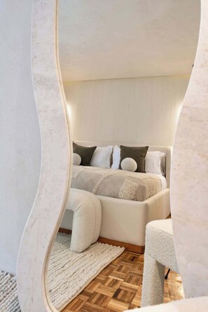 Ein modernes Schlafzimmer mit einem Bett, Kissen, einem Teppich und einem Sessel.