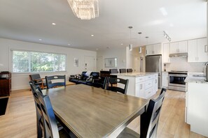 A modern kitchen with white cabinets, stainless steel appliances, and a dining area with a wooden table and chairs. - Tranquil 1-bedroom house in the heart of Victoria (Victoria)