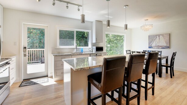Een moderne keuken met een groot eiland, hanglampen en een eetgedeelte met hoge stoelen.