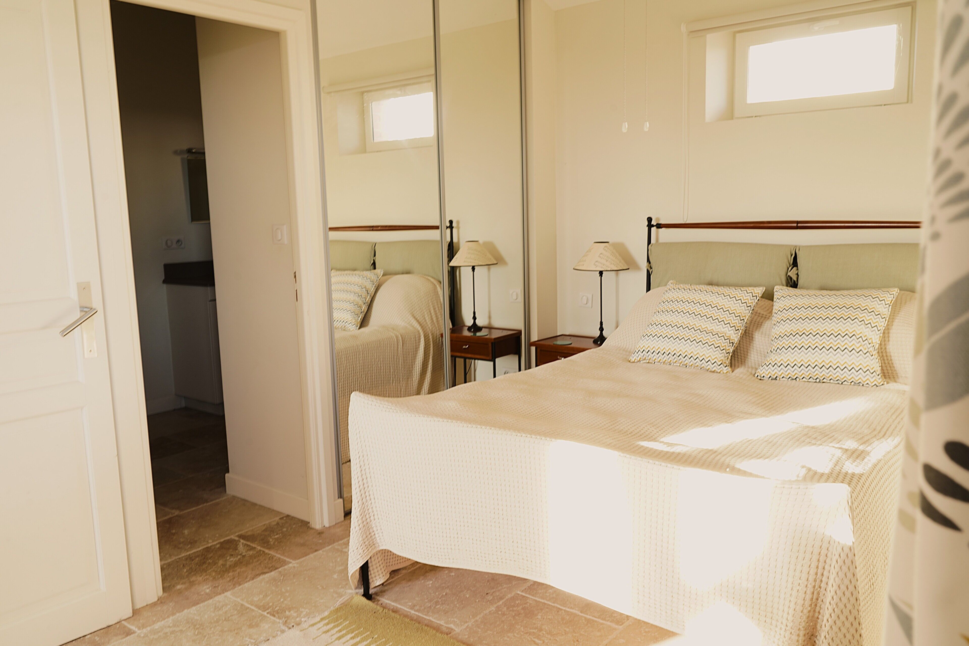 Une chambre à coucher avec un grand lit, une table de chevet, une lampe et un miroir.