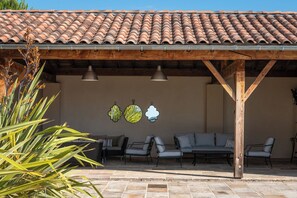 Un espace extérieur aménagé en patio, doté d’un toit en carrelage, d’une pergola en bois et de différents coins salon.