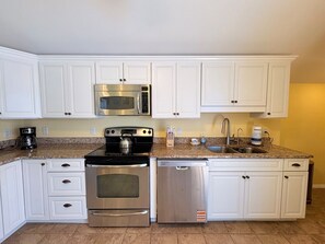 A kitchen with white cabinets, stainless steel appliances, granite countertops, and a dishwasher. - Blue Macaw North Captiva Island (North Captiva)