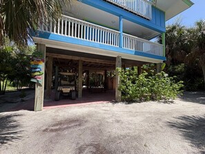 A two-story building with a covered outdoor area and a vehicle parked under it. - Blue Macaw North Captiva Island (North Captiva)