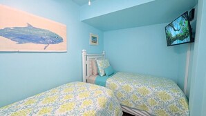Un dormitorio con dos camas, un televisor en la pared y un cuadro.