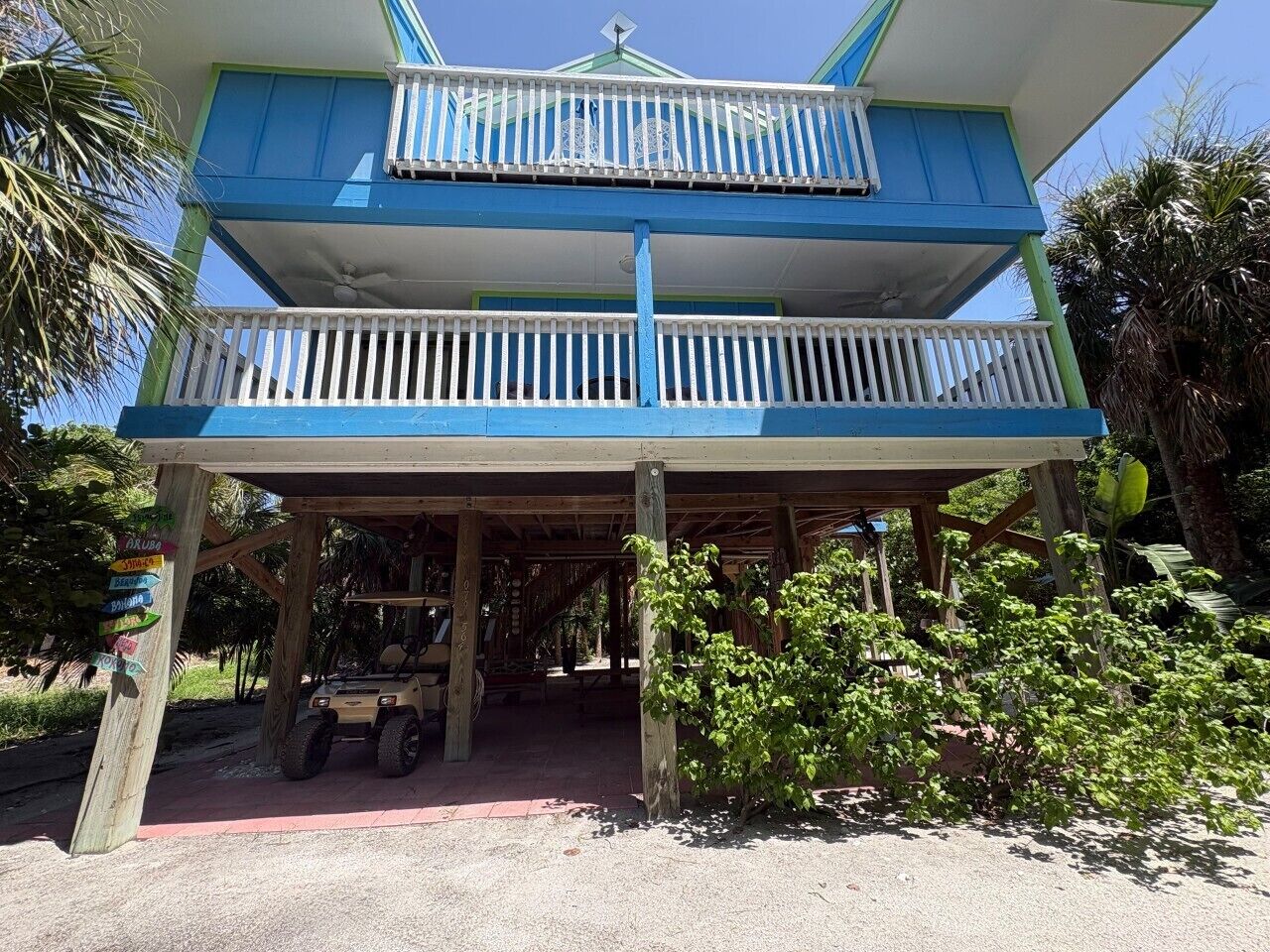 A two-story building with a balcony, a covered area, and a vehicle parked in front.