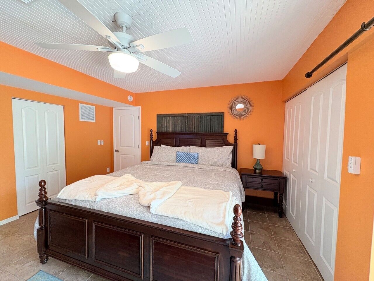 A bedroom with a bed, a ceiling fan, a nightstand, and a dresser.
