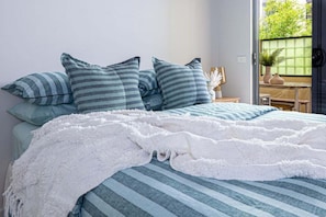 A bed with striped bedding, a white throw blanket, and matching pillows. - Magill Boho Retreat-2BR - free parking (Magill)