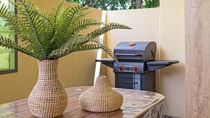 En terrasse med grill, to vævede vaser og en potteplante.