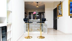 A bar area with two stools, a vase with flowers, and a painting on the wall. - Private Luxury Escape  Villa Reina Bella Pool, Balcony & Sleeps 14 (Villa hermosa)