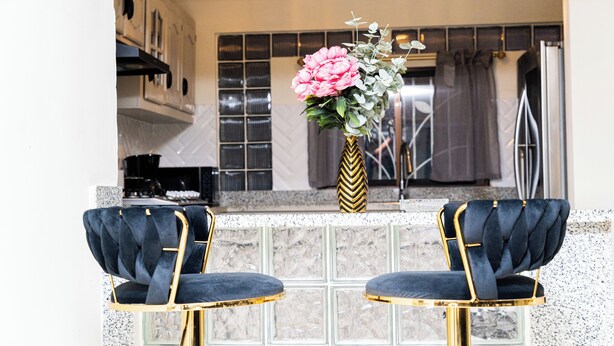 A kitchen with a marble countertop, two dark blue chairs with gold accents, and a vase with flowers. - Private Luxury Escape  Villa Reina Bella Pool, Balcony & Sleeps 14 (Villa hermosa)