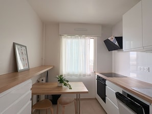 A compact kitchen with a wooden countertop, a small dining table, and a potted plant.