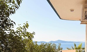 Ein Balkon mit Blick auf das Meer und die Berge, umgeben von Grün.