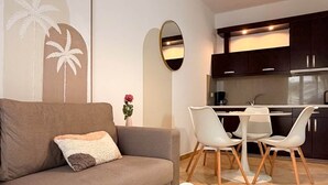 A modern living room with a sofa, a round coffee table, and a dining area with chairs and a table. - Alexis Beach (Pet Friendly) (Sarandë)