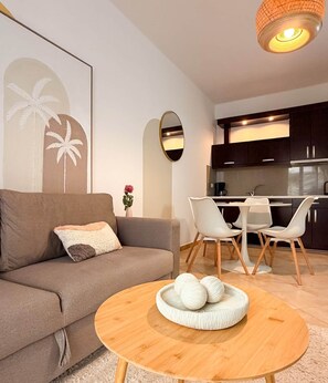 Ein modernes Wohnzimmer mit einer Couch, einem runden Couchtisch und einem Essbereich mit Stühlen und einem Tisch.