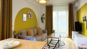 Een moderne woonkamer met een bank, een salontafel en een televisie op een standaard.