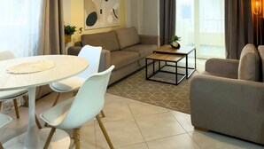 A modern living room with a sofa, a dining table with chairs, a coffee table, and a hanging light fixture. - Amelia Beach (Pet Friendly) (Sarandë)