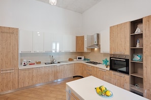 Una cucina moderna con mobili bianchi, un'isola centrale e un forno integrato.