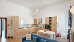 Eine moderne Küche mit Holzschränken, einer zentralen Kochinsel und einem blauen Sofa mit Zierkissen.