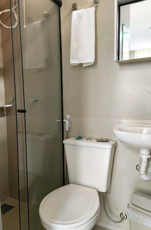Een badkamer met een douchecabine van glas, een toilet en een wastafel.