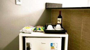 A compact minibar with a refrigerator, a bottle of wine, and some snacks. - Aeroband (Núcleo Bandeirante)