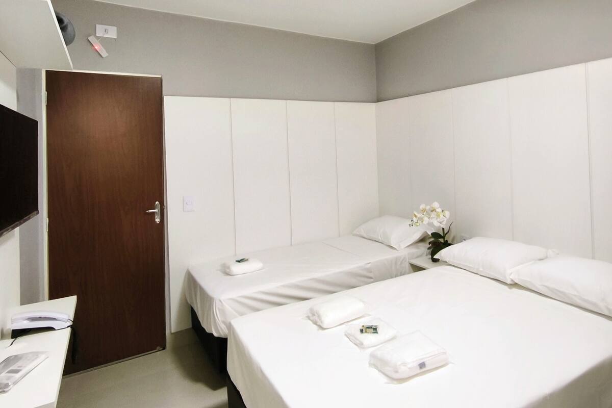 Une chambre d’hôtel avec deux lits, un bureau et une porte.