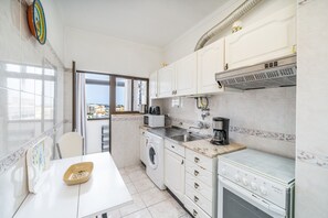 A compact kitchen with a washing machine, a stove, and a sink. - Apartment 'Candirocha C9' (Portimão)