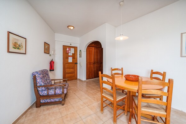 Un área de comedor con una mesa y sillas de madera, un sofá y una puerta con extintor.