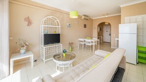 Uma sala de estar moderna com sofá, televisão, mesa de jantar e cadeiras.