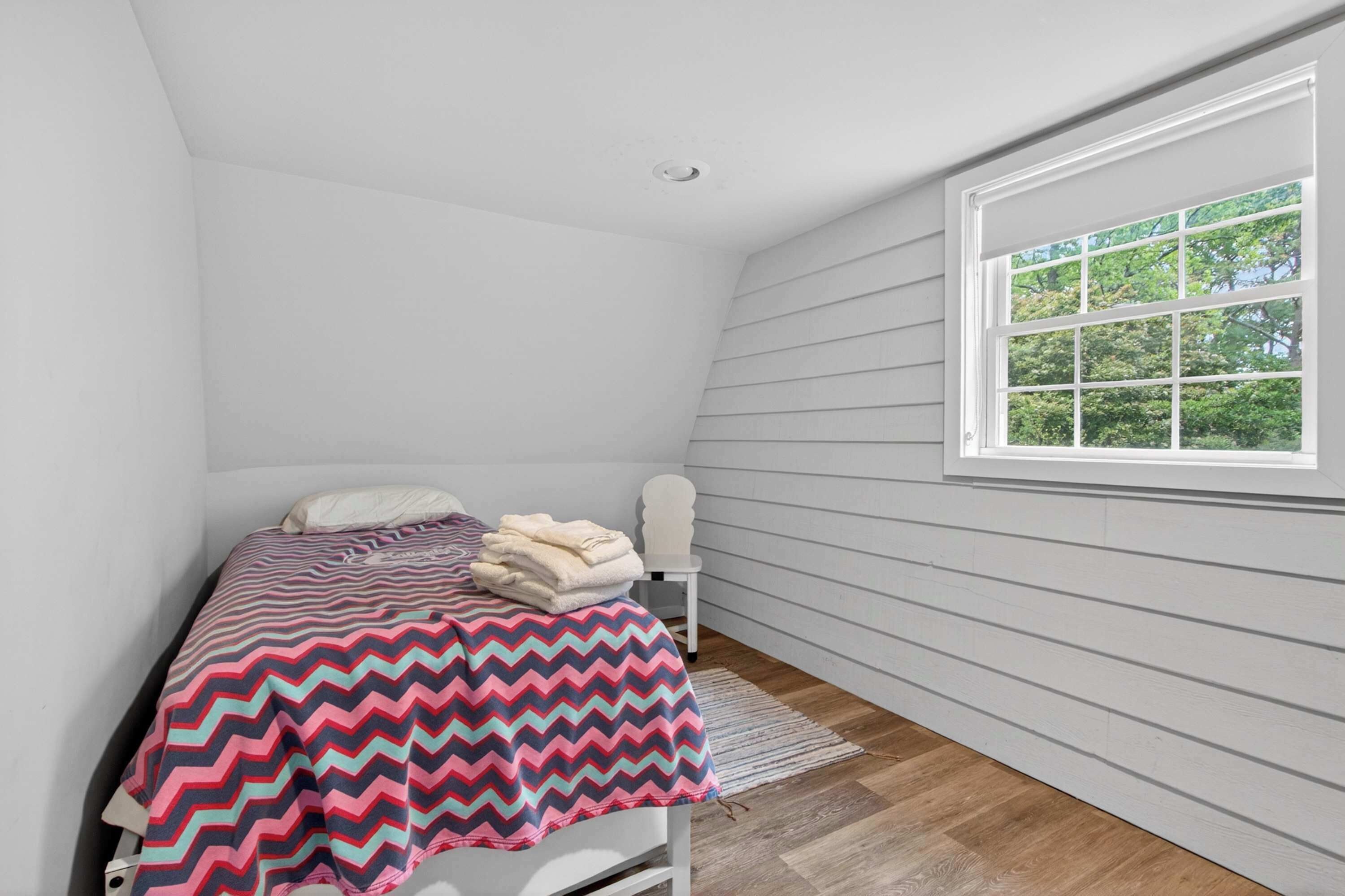 Une chambre à coucher avec un lit, une fenêtre et un mur blanc.