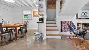 A modern interior with a wooden dining table, metal chairs, a staircase, and a bookshelf. - 401 142nd Street (Ocean City)