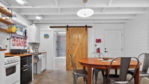 A kitchen with white cabinets, a wooden dining table, and a sliding barn door. - 401 142nd Street (Ocean City)
