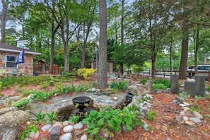 A garden with a pond, stone structures, and a flag.